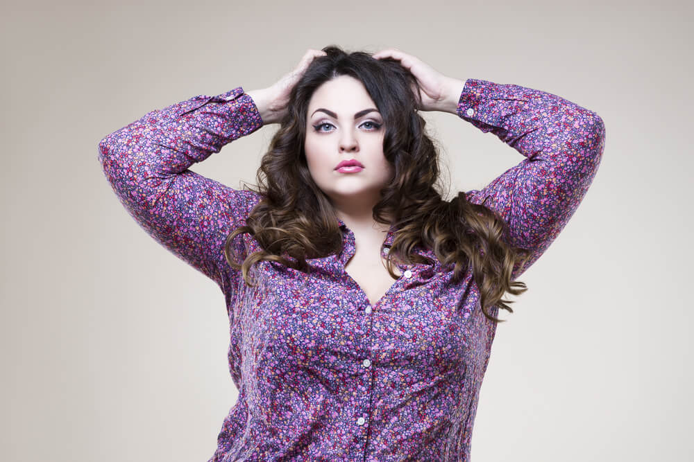 Charming curvy woman in purple shirt putting her arms on the head