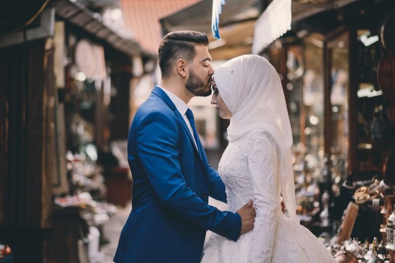 newly-wed husband kisses his muslima wife on her forehead