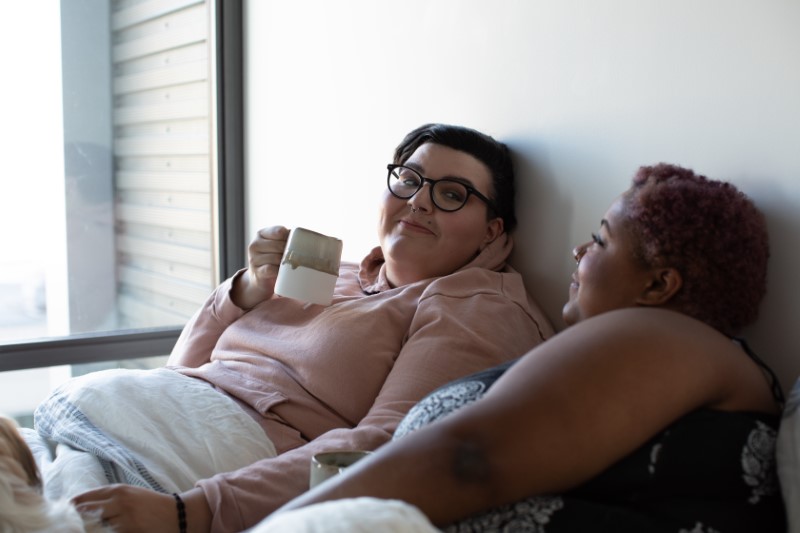 lesbian girlfriends in bed with a cup of coffee